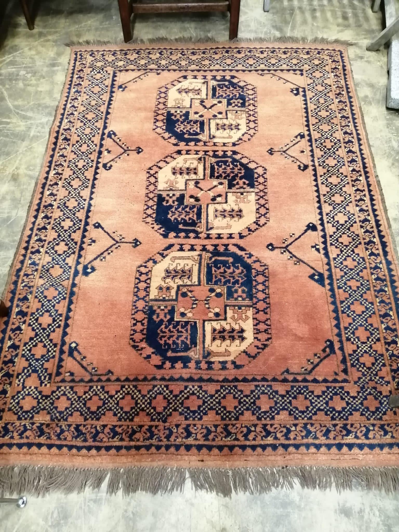An Afghan red ground rug, woven with three central octagons, 174 x 124cm